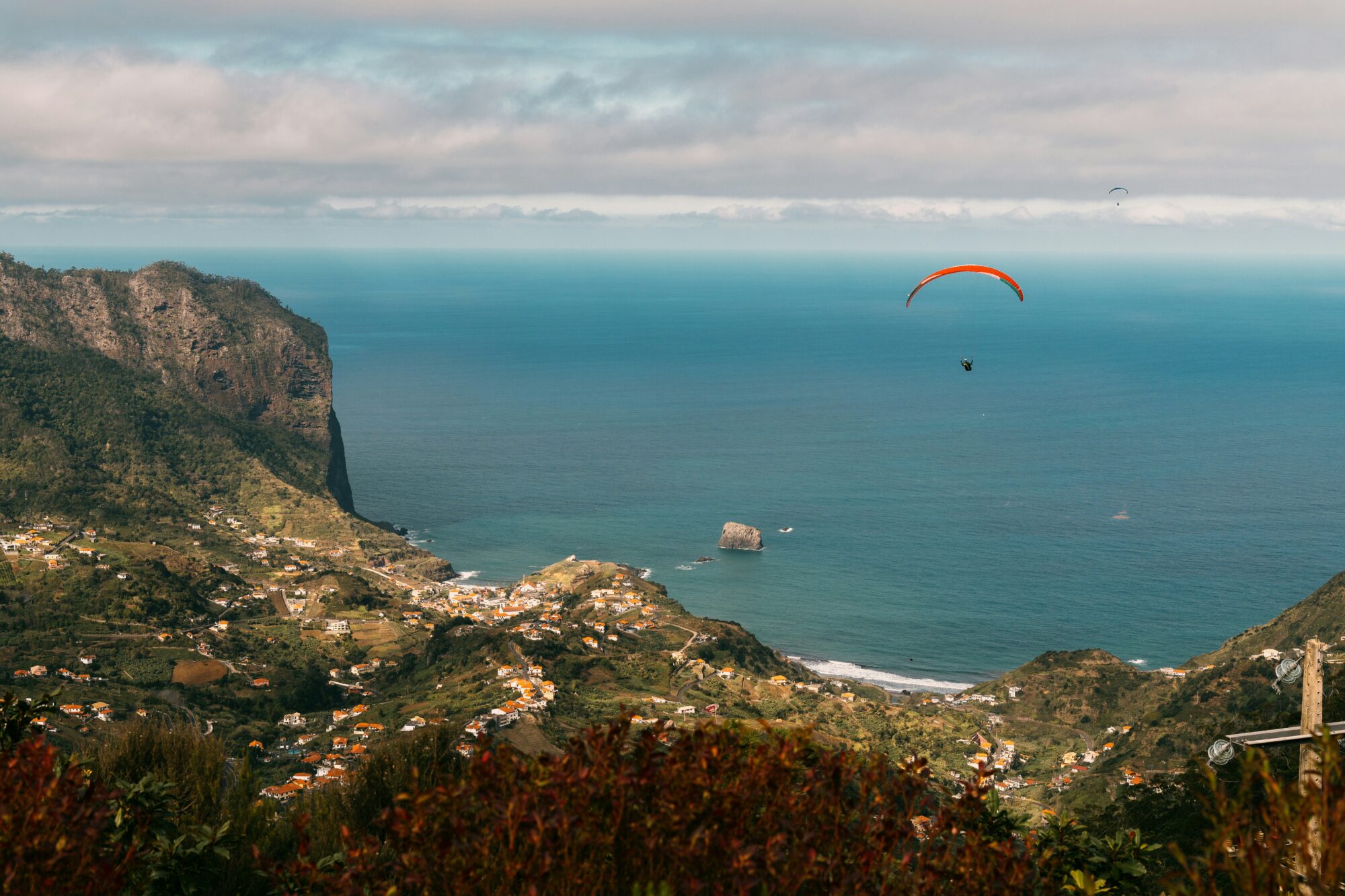 Person paragliding over mountains & sea