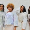 Four women wearing earth tones stand in a row