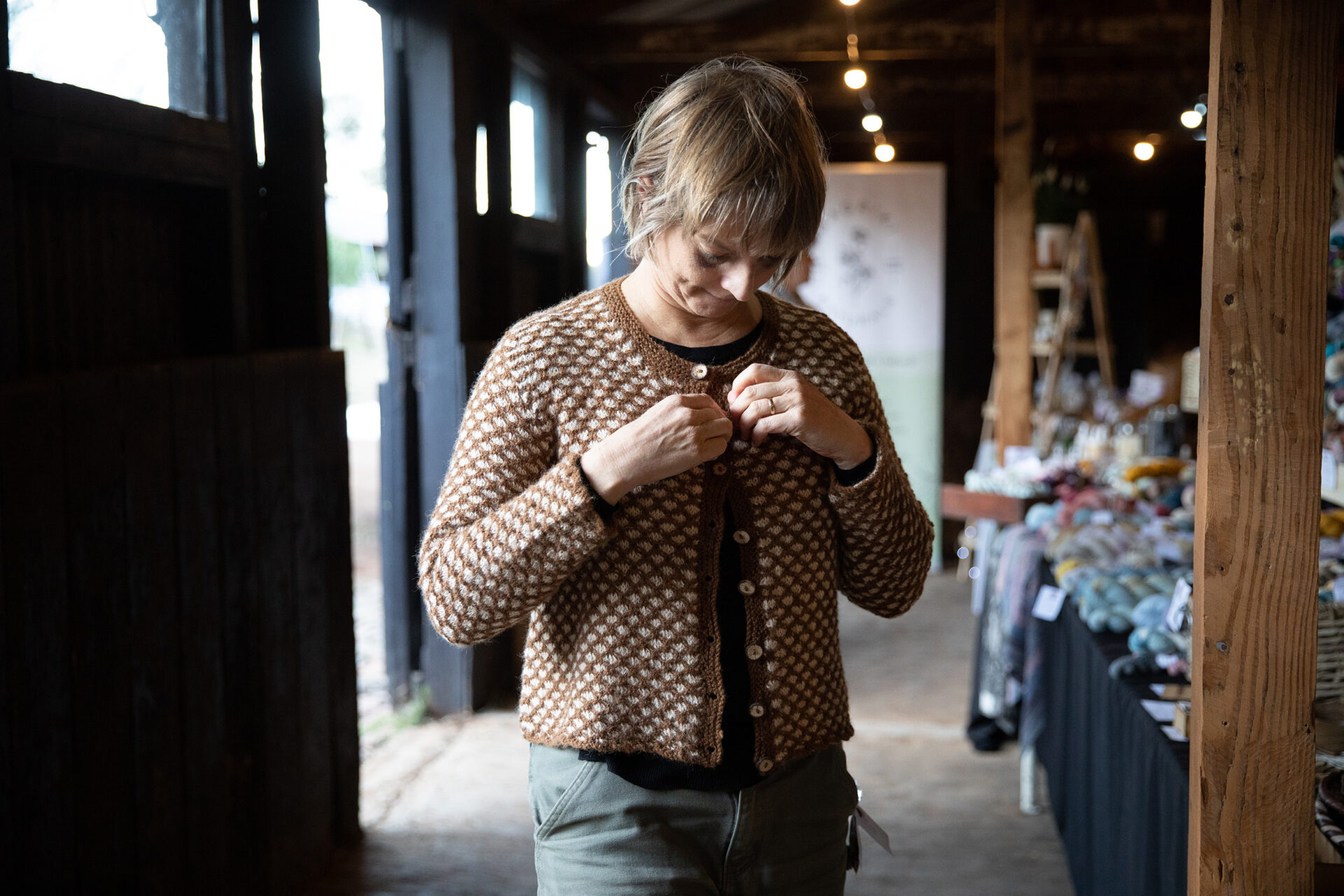 A woman trying on an alpaca farm-to-fibre-to-fashion cardigan