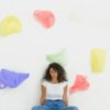 Woman Sitting Against the Wall Decorated with Colorful Plastic Bags